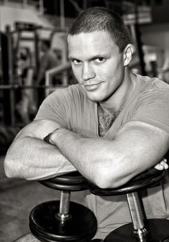 Portrait of a man with dumbbells in fitness club