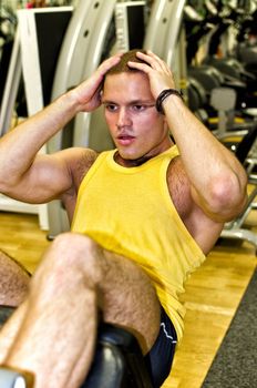 Portrait of handsome bodybuilder doing exercise in fitness club