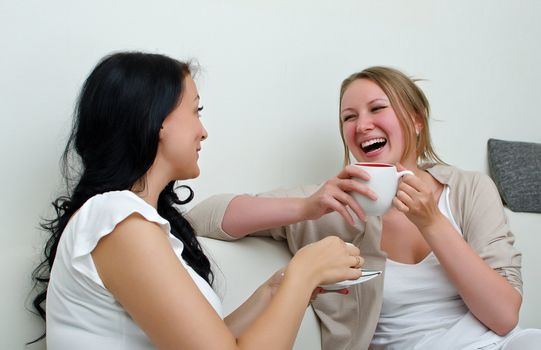 Two women friends chatting over coffee at home