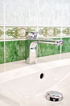 Green interior of bathroom with faucet and sink.