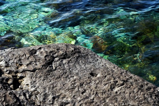 Background of a rough textured rock alongside cool pure fresh water in a rock pool