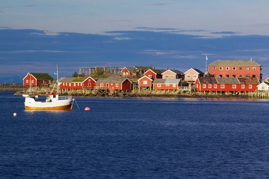 Red fishing rorbu huts and fishing boat in town of Reine on Lofoten islands