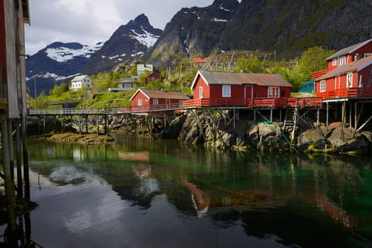 Typical red rorbu fishing huts on Lofoten islands in Norway reflecting in fjord