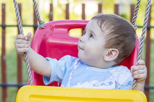 9-month old baby boy  in a swing outdoors