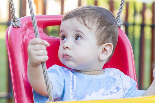 close-up of 9-month old baby boy  in a swing outdoors