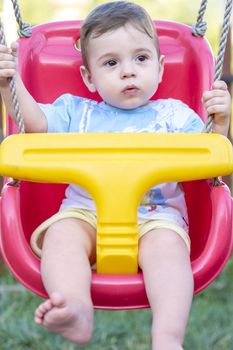 close-up of 9-month old baby boy  in a swing outdoors