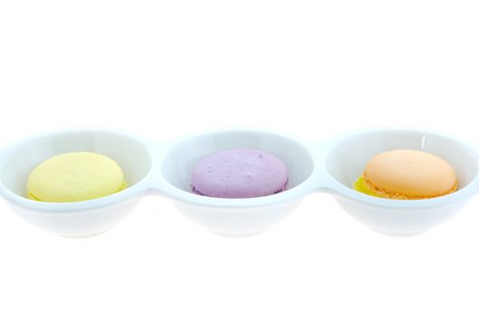 French macaroons in bowl on white background