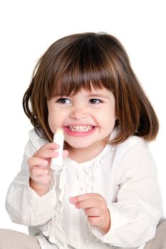 Portrait of cute little girl holding lip balm. Isolated on white background.