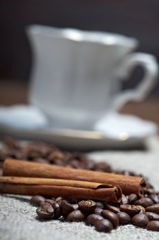 Coffee cup with cinnamon and coffee beans background