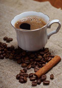 Coffee cup with cinnamon and coffee beans background