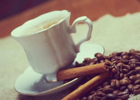 Coffee cup with cinnamon and coffee beans background