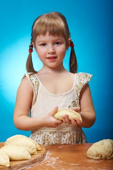 Smiling little girl kneading dough at kitchen with baking a pie