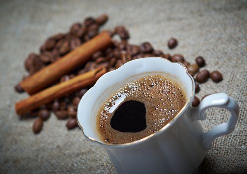 Coffee cup with cinnamon and coffee beans background