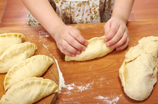 Smiling little girl kneading dough at kitchen .Detail of hands kneading dough