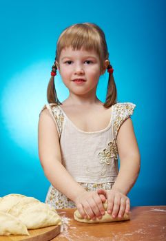 Smiling little girl kneading dough at kitchen with baking a pie