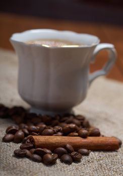 Coffee cup with cinnamon and coffee beans background