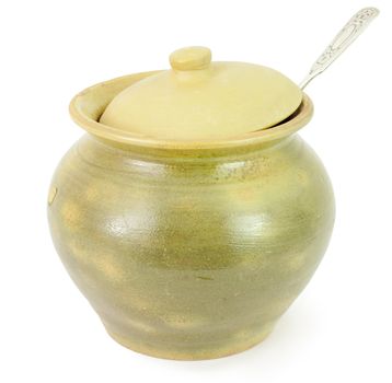 Old ceramic pot with a spoon isolated on a white background