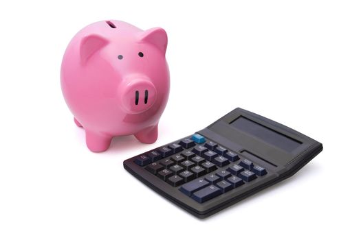 Pink piggy bank is near the calculator on white background.
