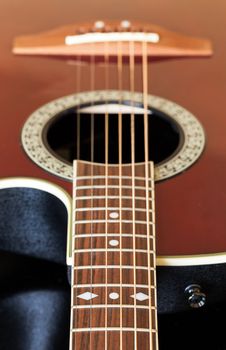 Macro shot down the fretboard of acoustic guitar with shallow depth of field