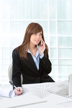 Portrait of Attractive young business woman in office at desk with plans.