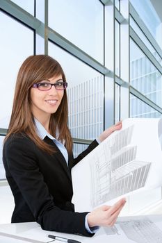 Portrait of Attractive young female architect with plans in office.