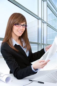 Portrait of Attractive young brunette architect at desk with plans.