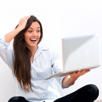 Young attractive woman  with surprised face expression  sitting on floor with laptop.