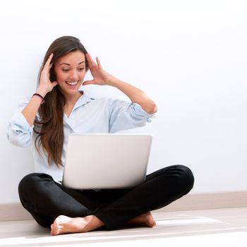 Young attractive woman sitting on floor with laptop.