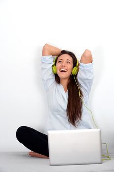 Happy young woman laughing with laptop and earphones.