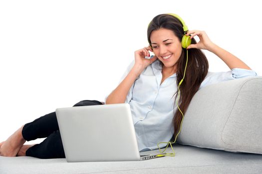 Young attractive woman sitting on couch with laptop and earphones.