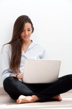 Young attractive woman sitting on floor with laptop.