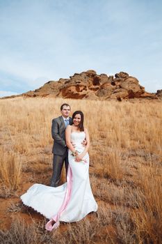 bride and groom in the field with mountain