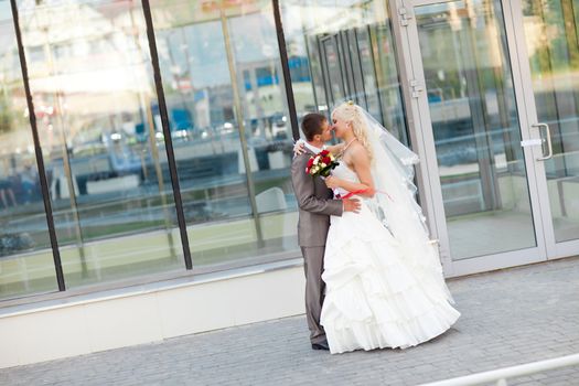 bride and groom kiss by the wall