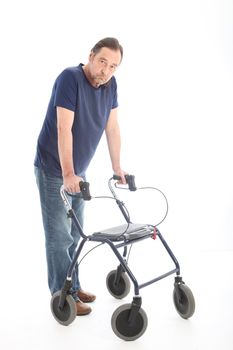 Middle-aged man walking leaning his arms and weight on a medical walker for support and stability following an illness, injury or disability 