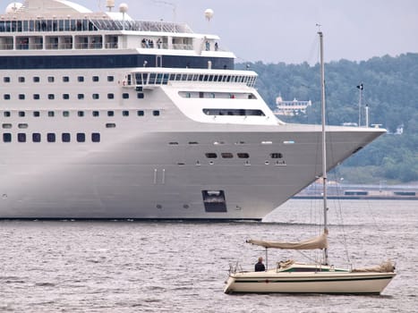 Cruise ship leaving or arriving, with a little sailboat alongside.