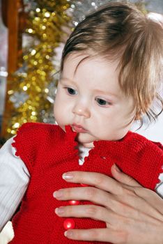 Cute little kid in the red vest in the hands of parents.