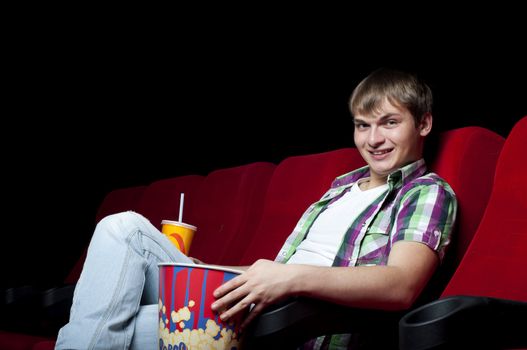 man in a movie theater, watching a movie and drink a drink