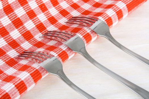 Shiny stainless steel forks on checkered fabric