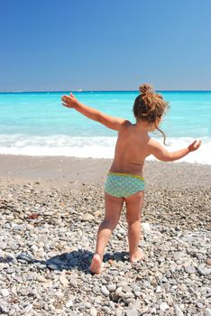 The girl going to sea on a stony beach.