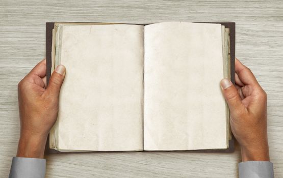 hands and opened vintage book over table