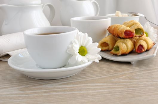 A cup of tea with homemade croissants filled with colorful jelly