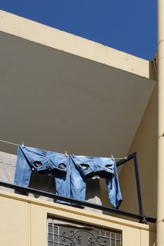 Two pairs of blue jeans drying on balcony sunlight