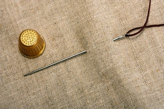 Needle silver , thimble and thread in background fabrics concept