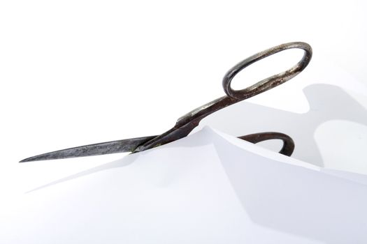 Old rusty steel scissors cut paper on white background