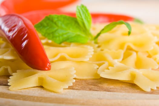 Golden raw dried Italian pasta with other ingredients on kitchen desk.