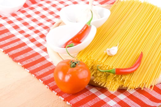 Golden raw dried Italian pasta with other ingredients on kitchen desk.