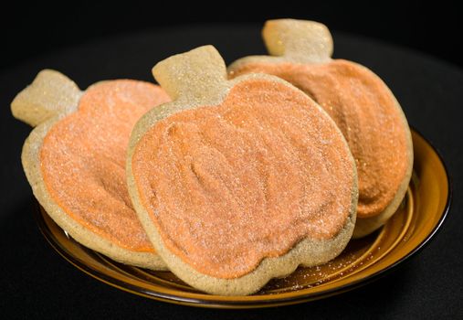 Homemade pumkin cookies on isolated black background.