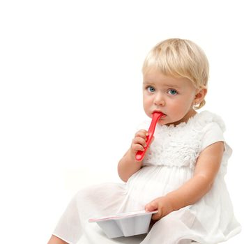Blue eye baby girl sitting with red spoon and boring face expression . Isolated on white background.