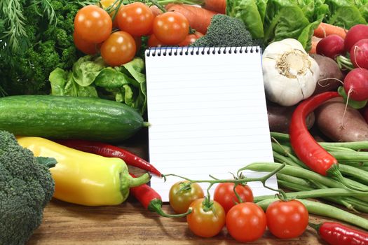 Ruled shopping list with fresh vegetables on a wooden background