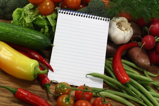 little ruled shopping list with vegetables on a wooden background